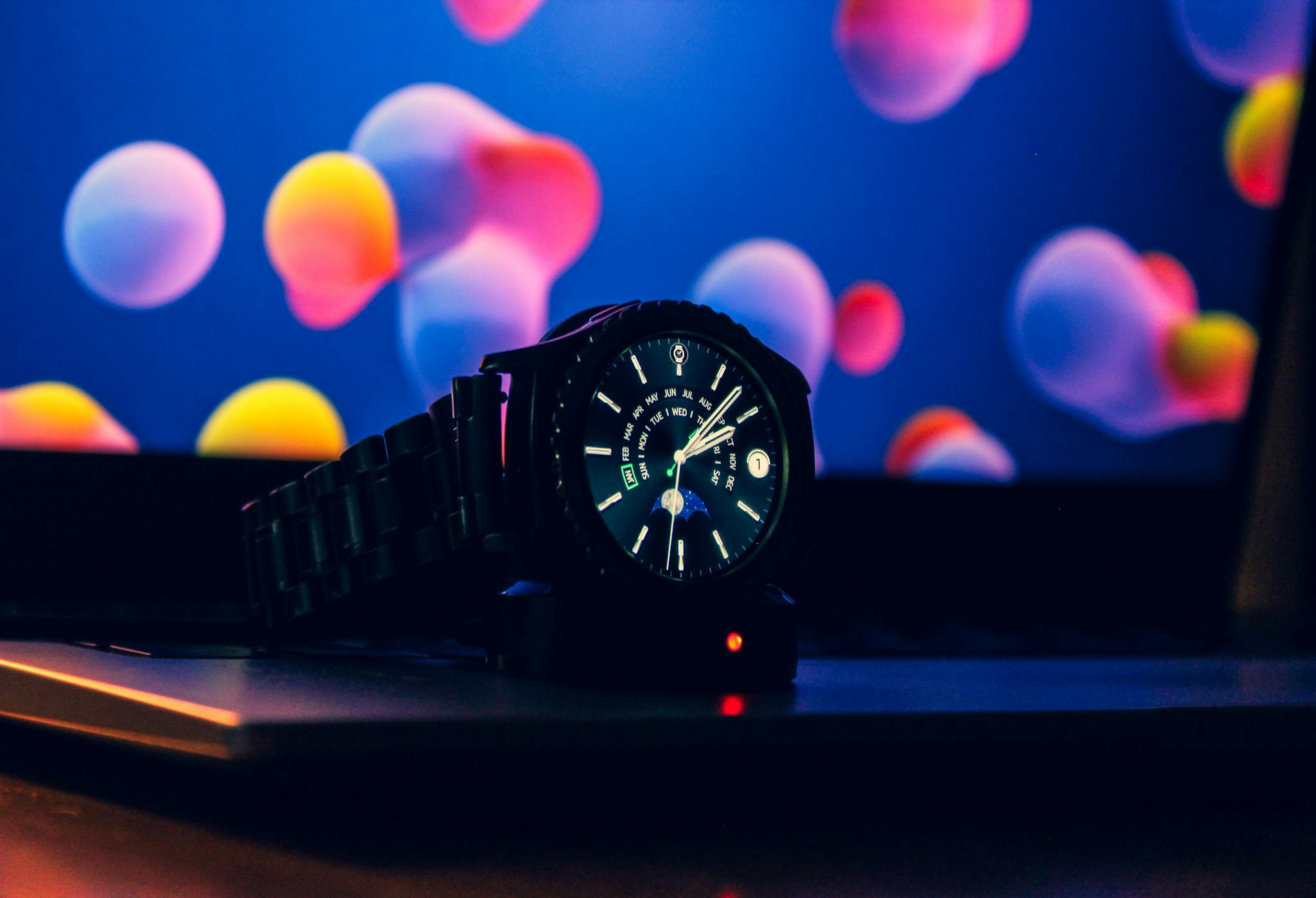 Close-up of a modern wristwatch on a laptop with vibrant digital wallpaper.