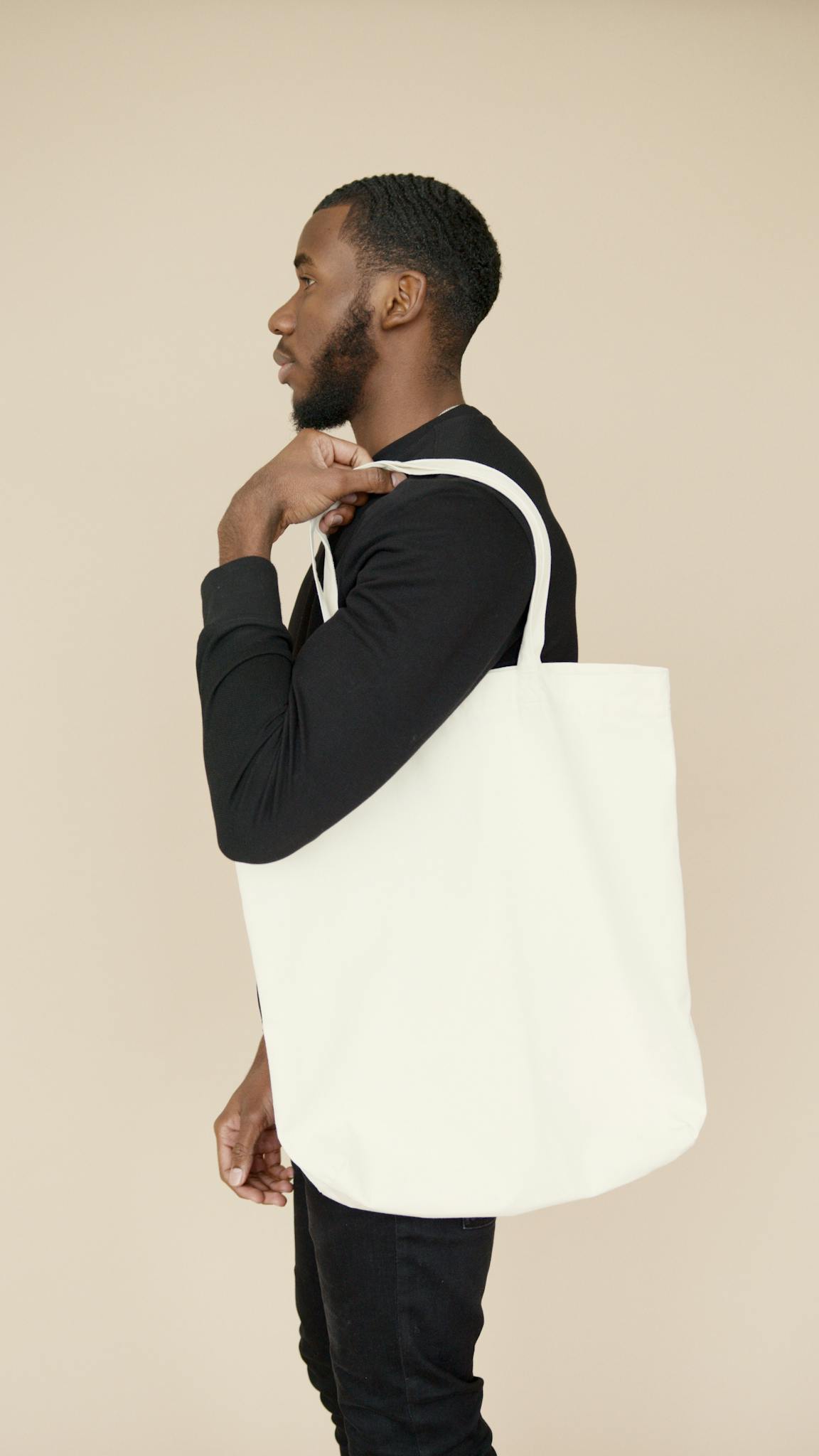 Profile of a young man holding a white tote bag, showcasing eco-fashion.